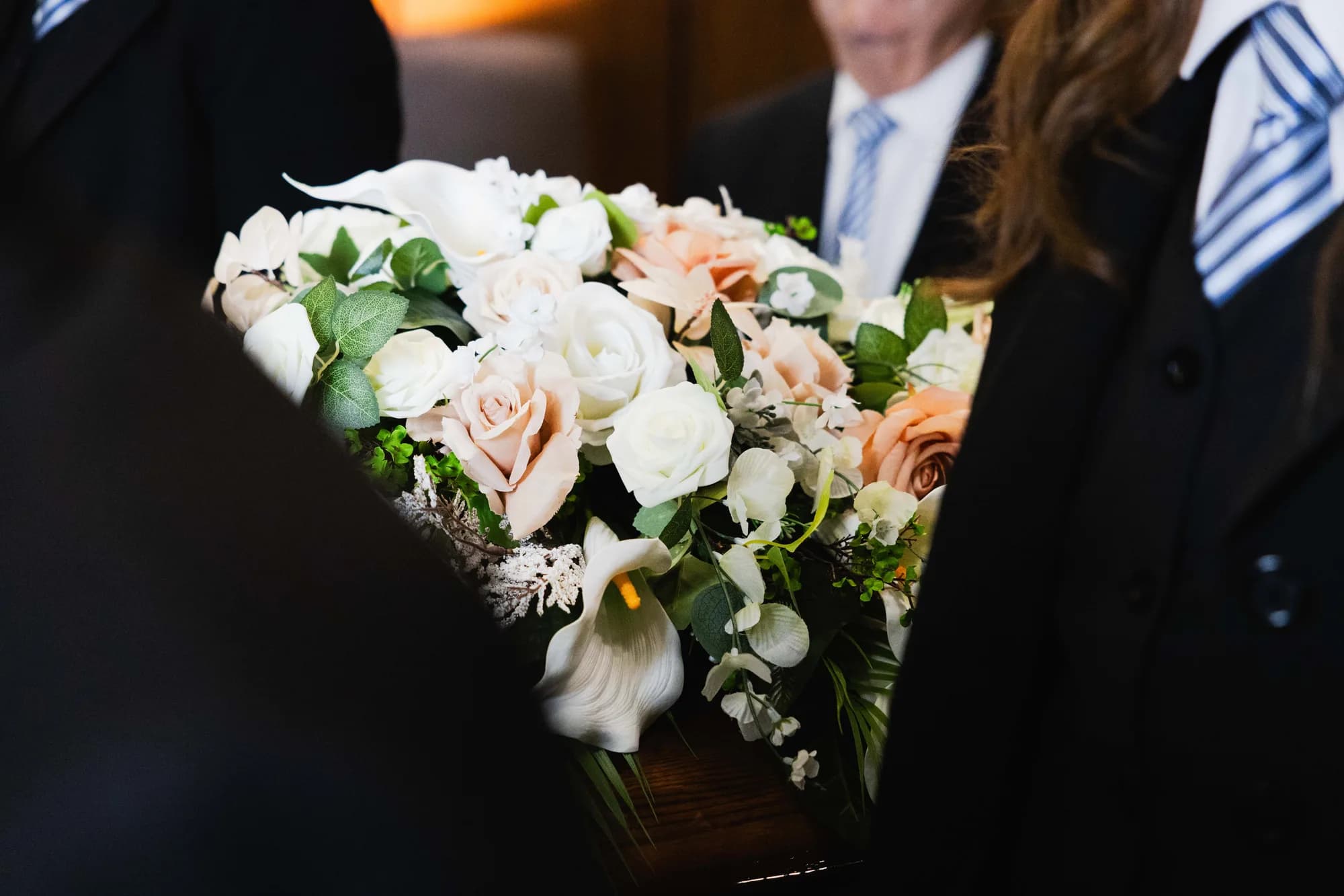 A floral spray on a casket in the Generations chapel, directors standing by
