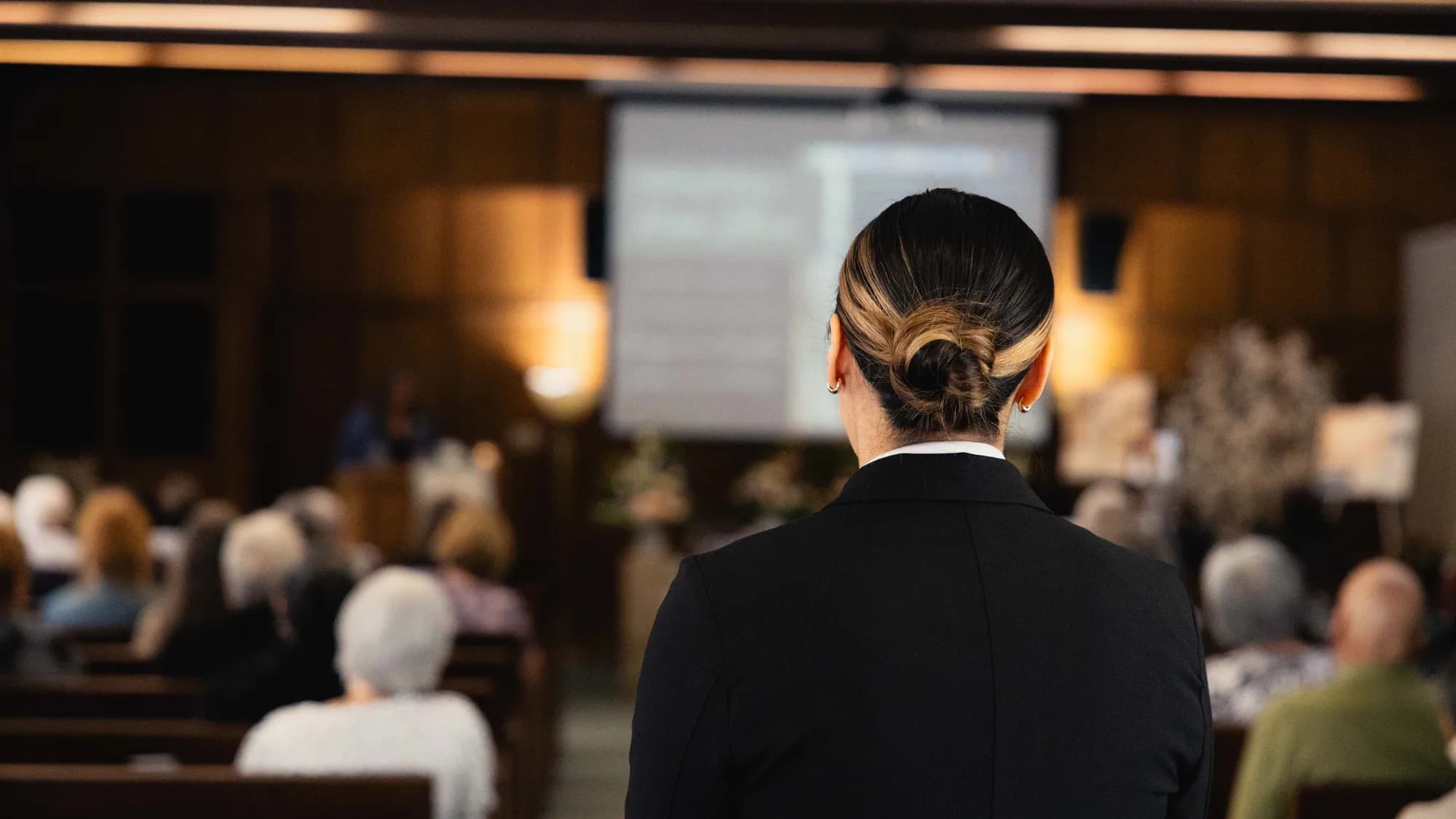 A Generations funeral director facing a seated congregation in the chapel.