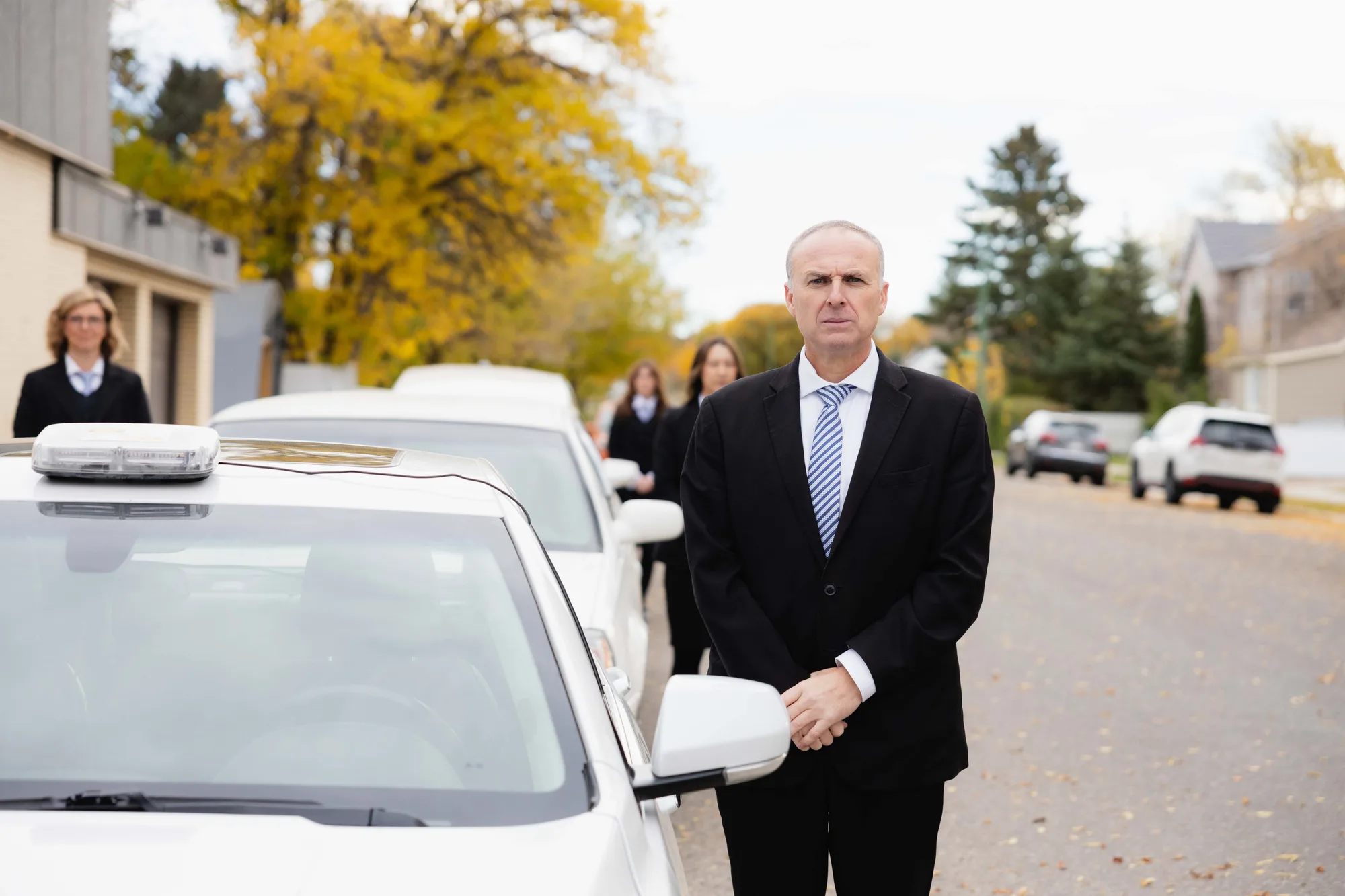 A Generations funeral director waiting at the limousine door before a service